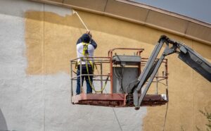 a professional painter painting a building's exterior white
