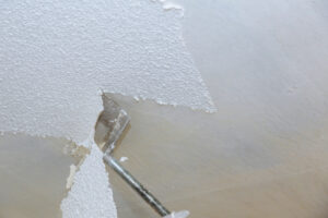 a professional scraping off a popcorn ceiling